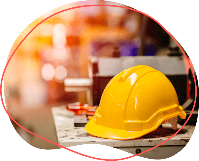 Žltá prilba spočíva na pracovnom stole a symbolizuje bezpečnosť uprostred rozmazaného zhonu priemyselného prostredia a dokonale zvýrazňuje zameranie na bozp školenie.