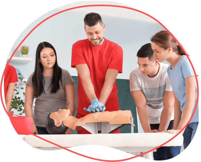 Skupina učiaca sa KPR na figuríne s mužom predvádzajúcim stláčanie hrudníka.