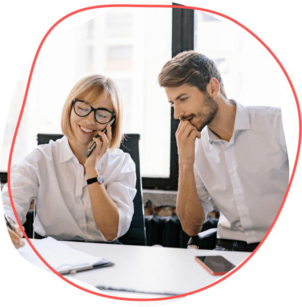 Dvaja ľudia v bielych košeliach diskutujú o Finmajsterových poznatkoch pri skúmaní dokumentov v kancelárii. Jeden telefonuje a obaja sú intenzívne sústredení.