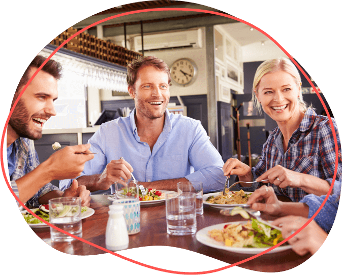 Skupina ľudí sa usmieva a vychutnáva si spoločné jedlo pri reštauračnom stole a pomocou svojich stravných lístkov si vychutnáva každé chutné jedlo.