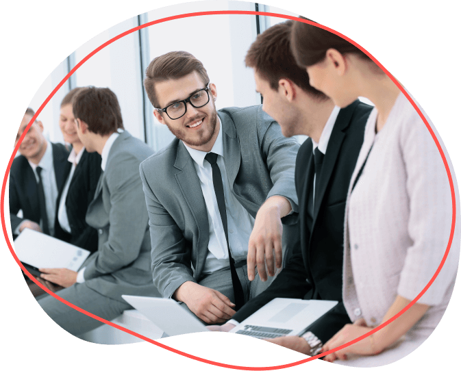 Skupina profesionálov v formálnom oblečení sedí a rozpráva sa, niektorí držia papiere a notebooky a diskutujú o výhodách svojho najnovšieho projektu.